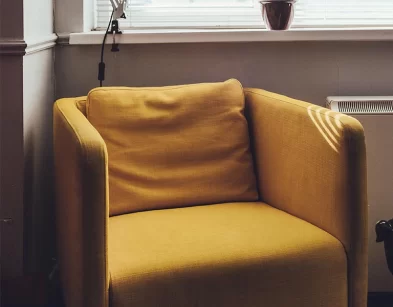 A yellow armchair in front of a window.