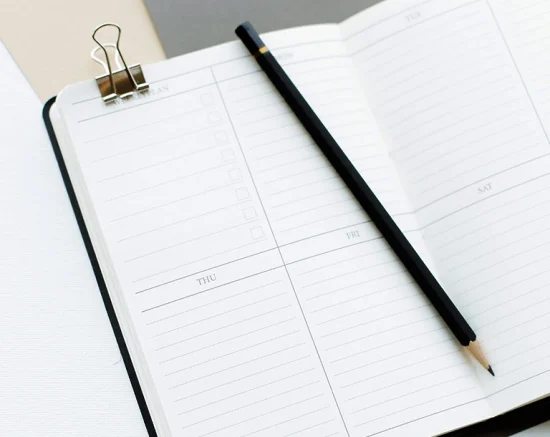 A black pencil lying across an open diary.